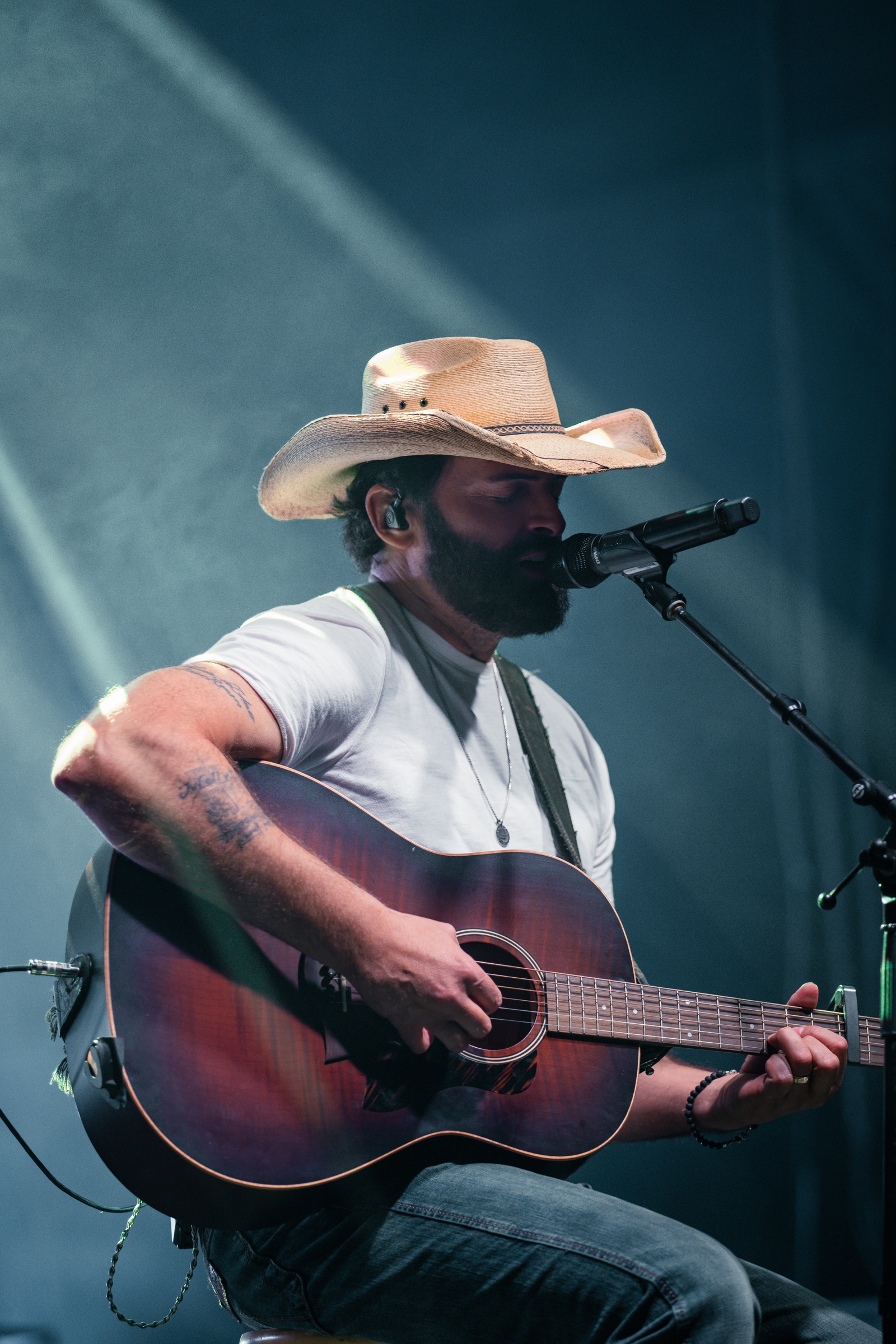 Dean Brody seated with an acoustic guitar during his live performance