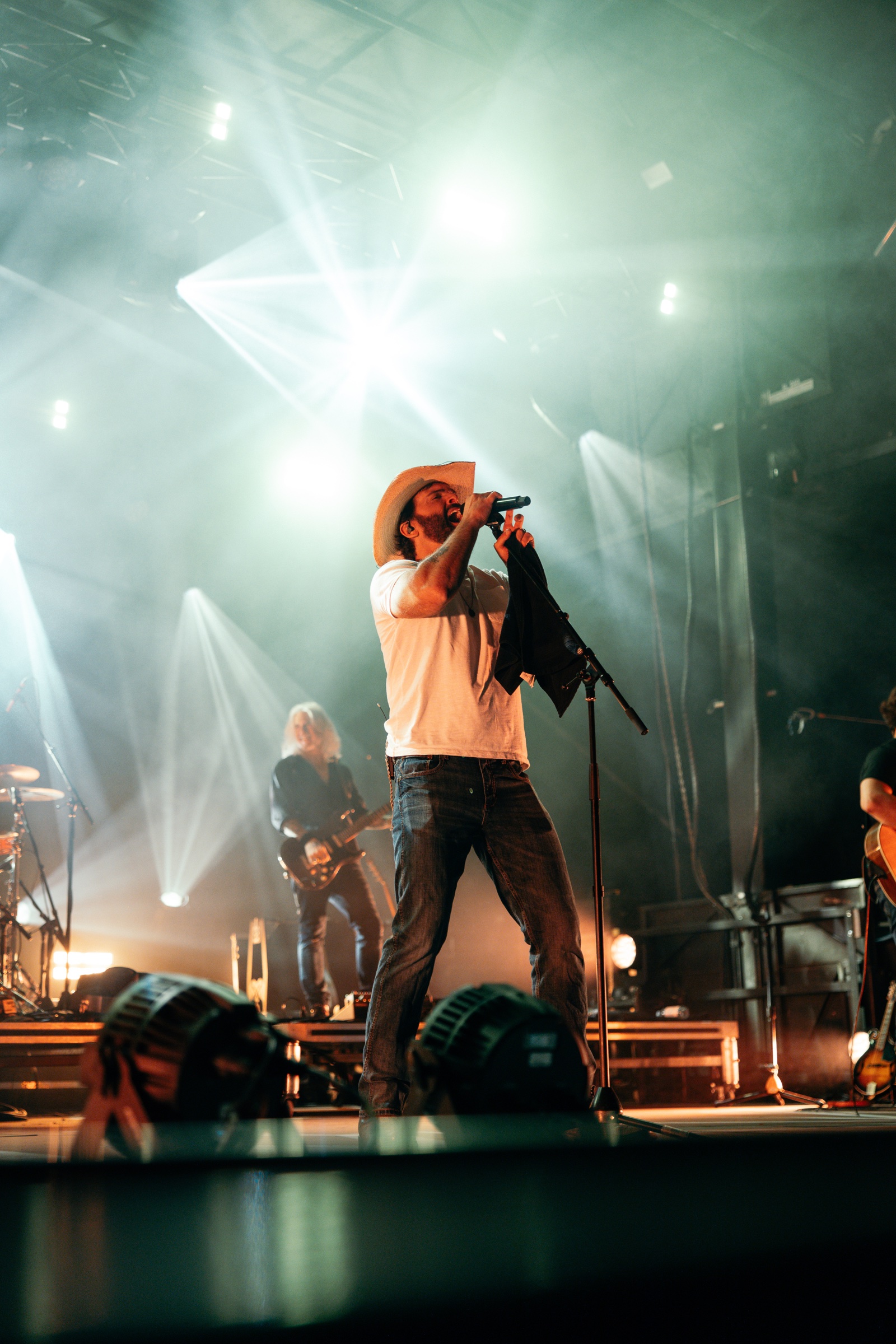 Dean Brody performing beneath dramatic white stage beams