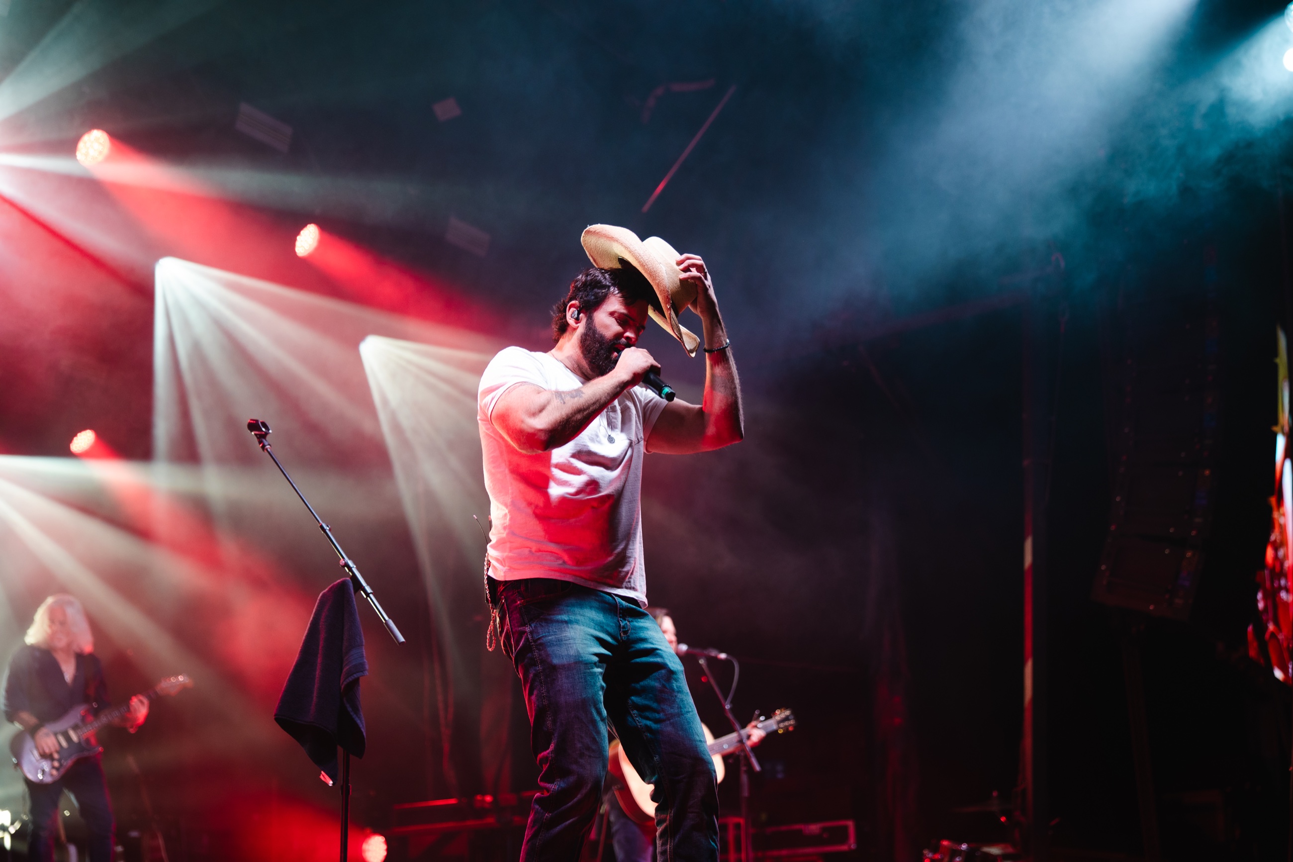 Dean Brody performing live beneath red and blue stage lights