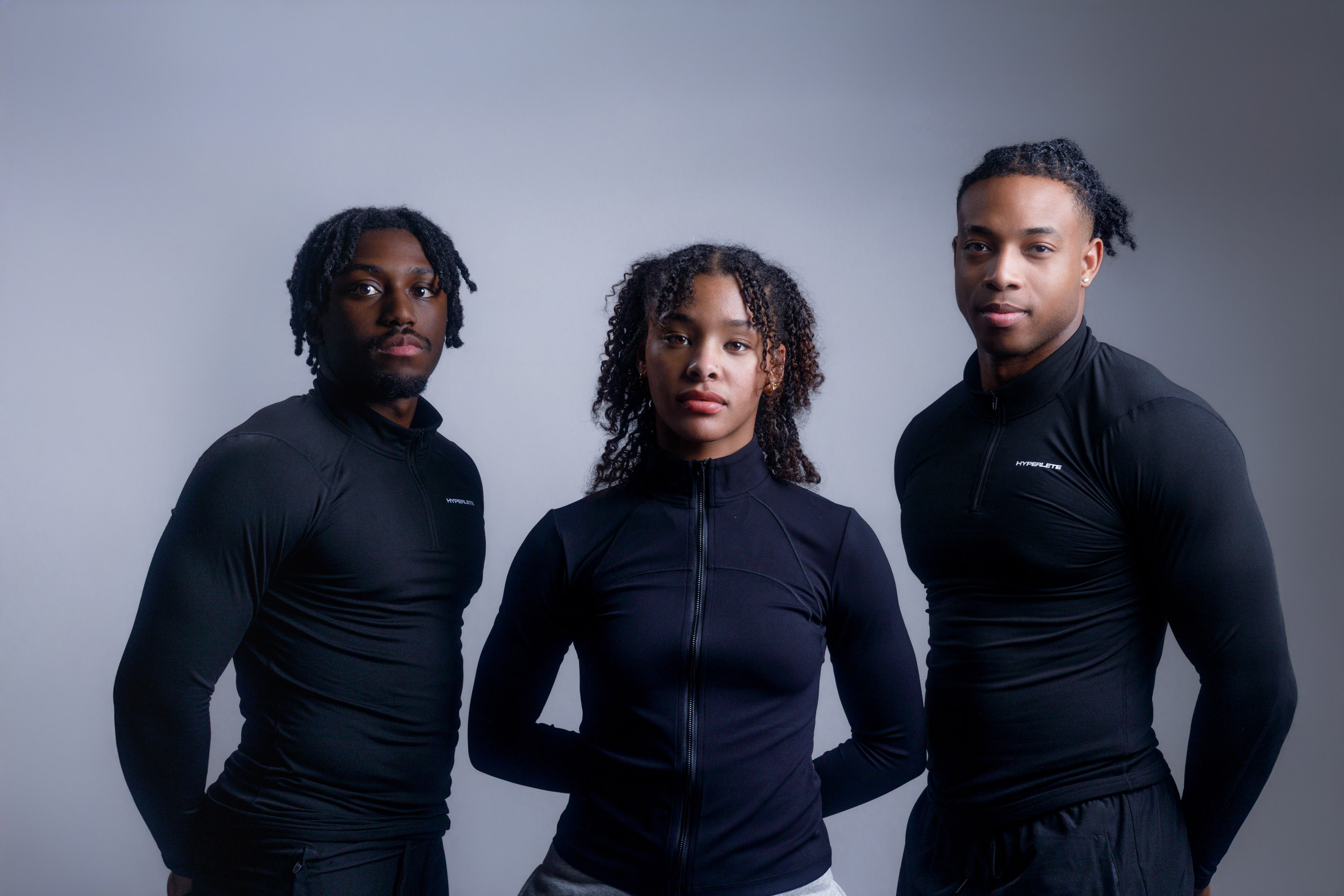 Three athletes modeling coordinated black performance apparel