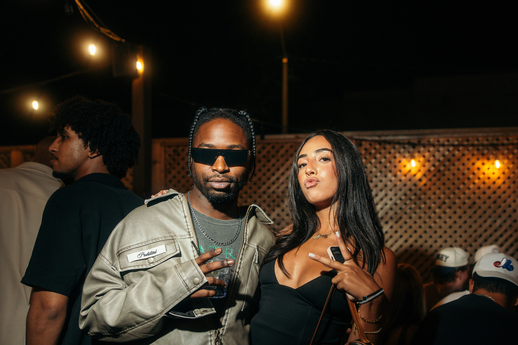 Stylish two-person nightlife portrait beneath warm patio lights
