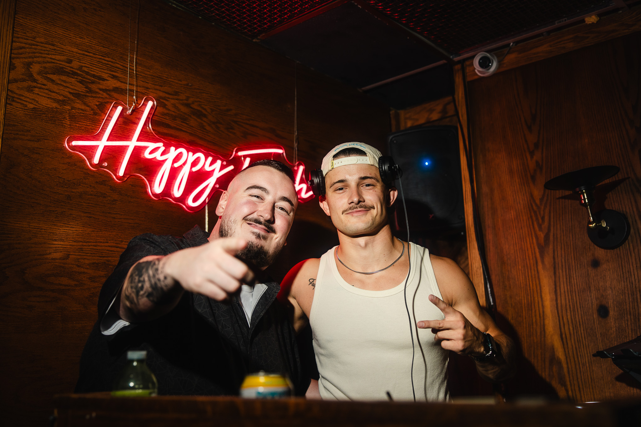 DJ and guest photographed in front of a red neon club sign