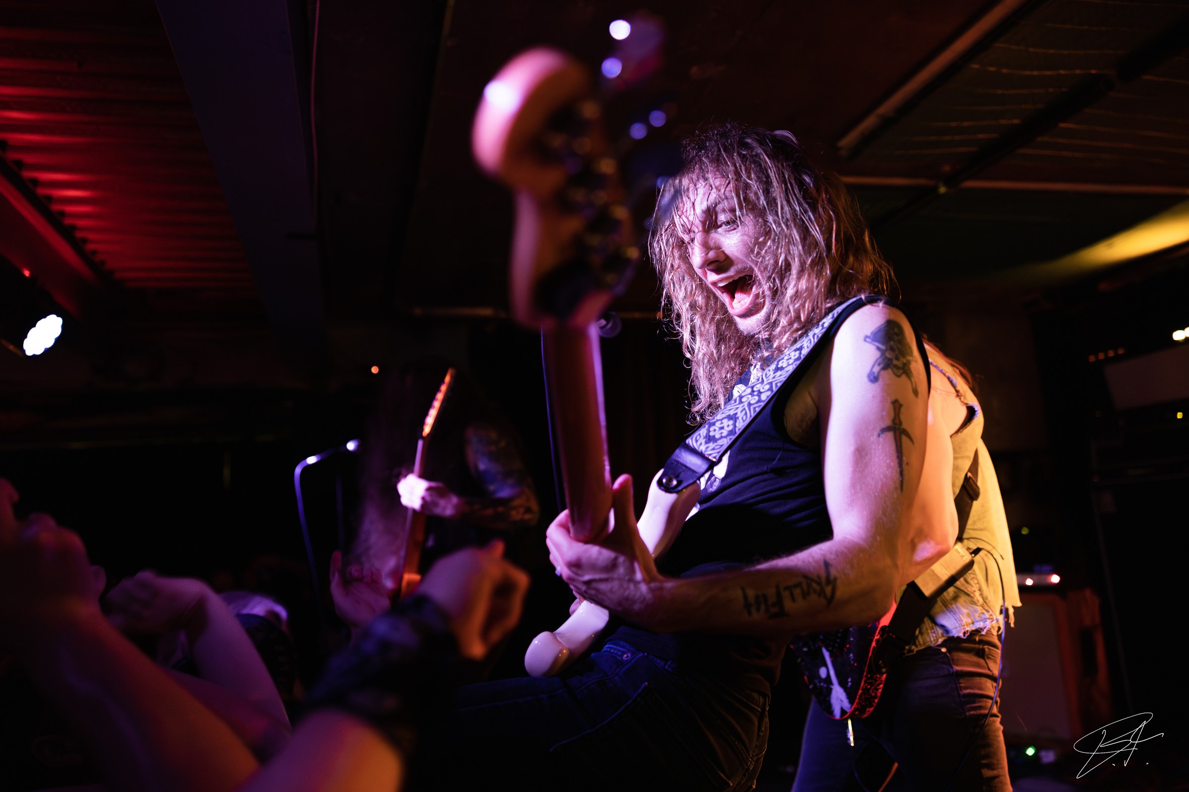 Guitarist performing under vivid purple stage lighting