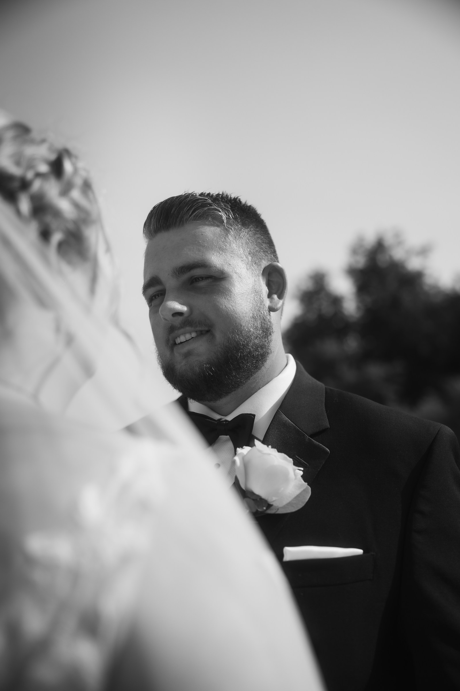 Black-and-white wedding portrait framed through the bride's veil