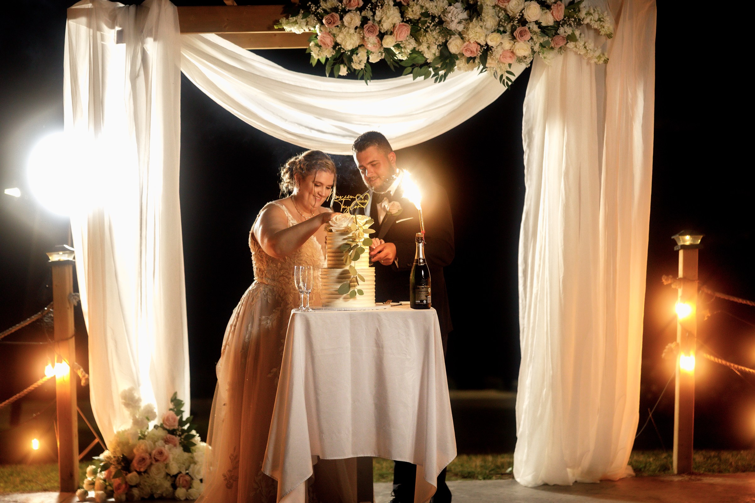 Newlyweds cutting their cake beneath an illuminated arch