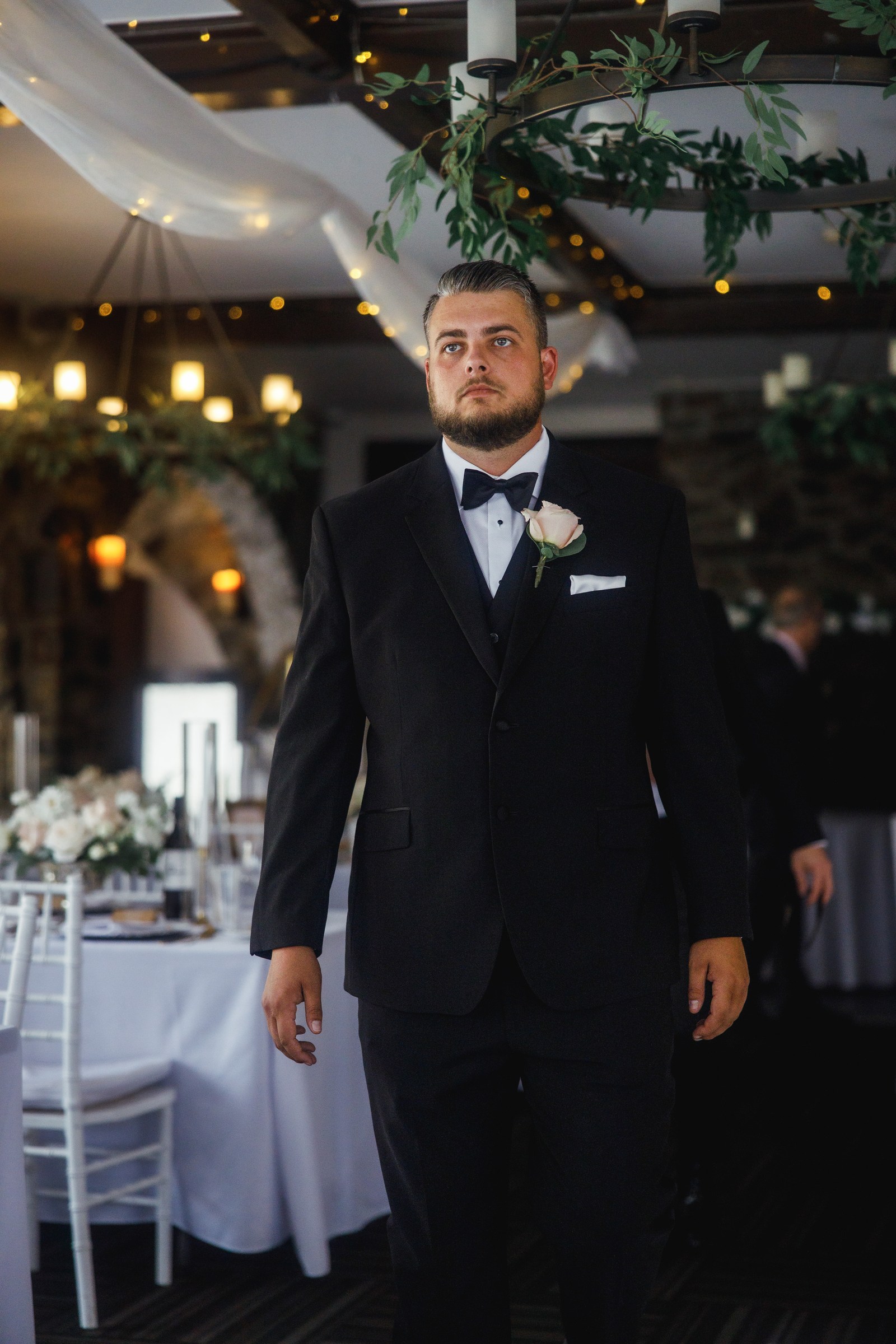 Groom portrait beneath warm reception lights